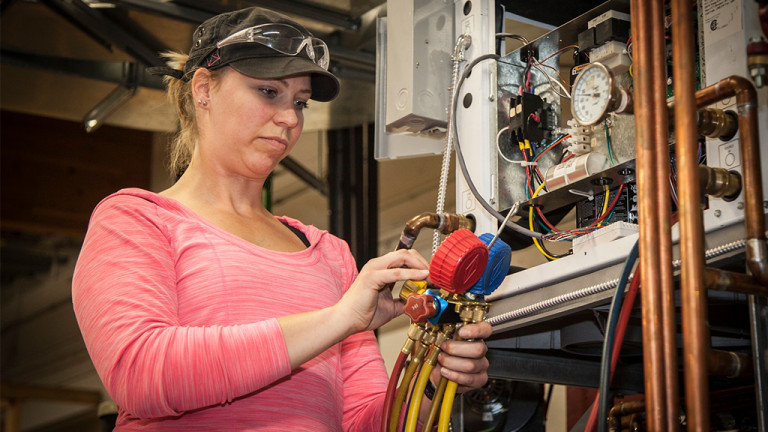 A woman checks over the pressure values on a industrial sprinkler system..