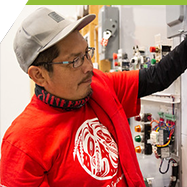 An indigenous student checks a circuit panel in the electrical shop.