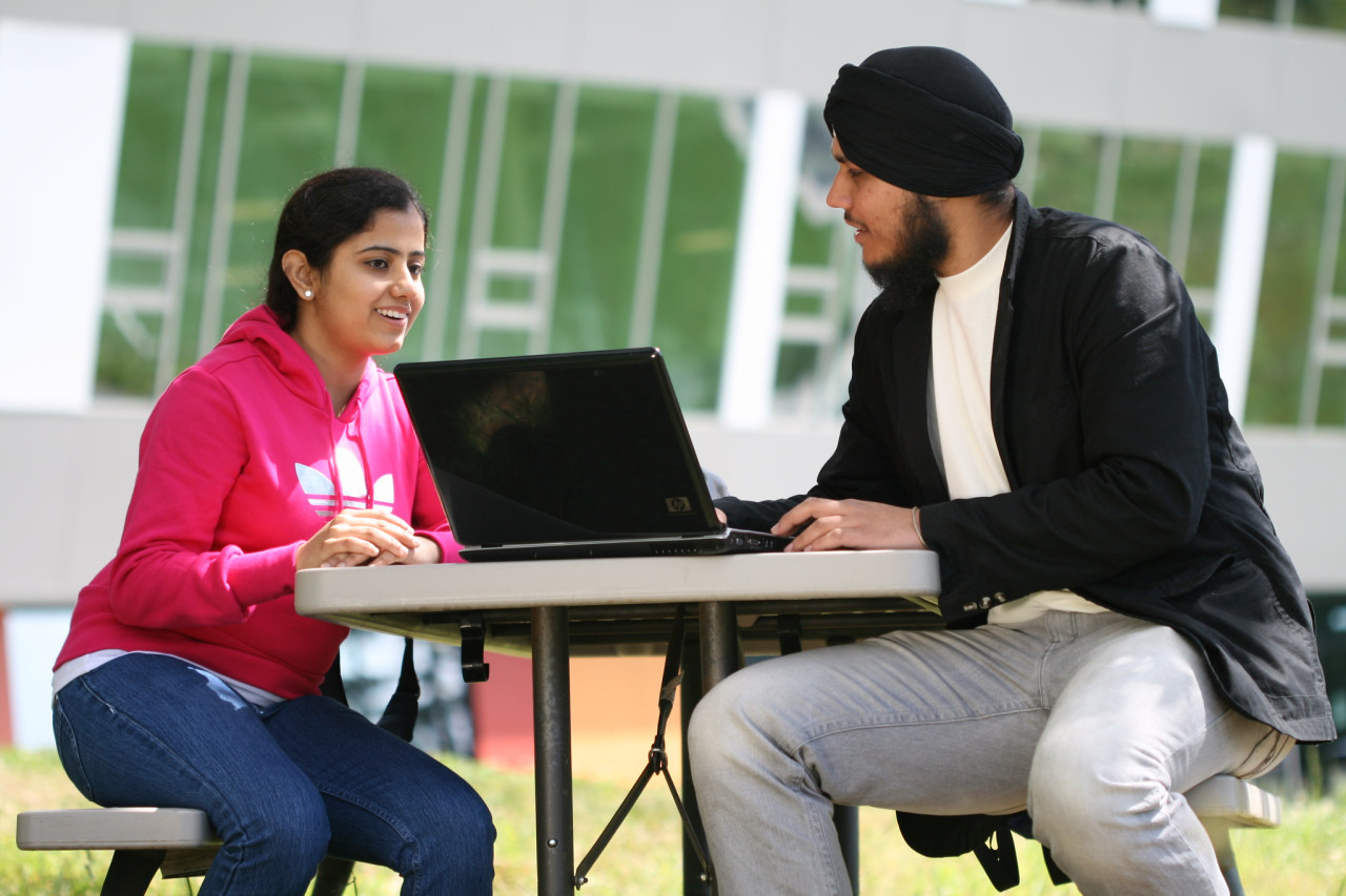 two students working on a computer outside