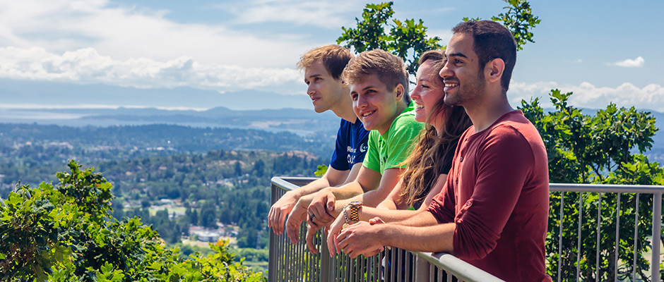 A group of students look out over Victoria from a balcony on a sunny day