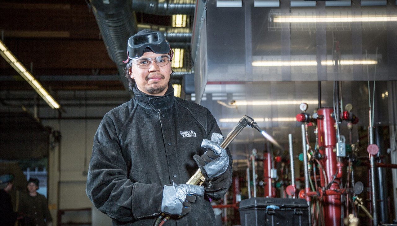 A young Indigenous man working in the welding shop.