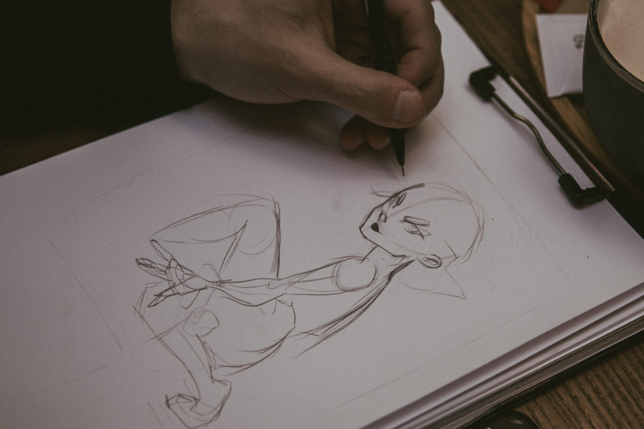 close up of hand sketching a crouched figure