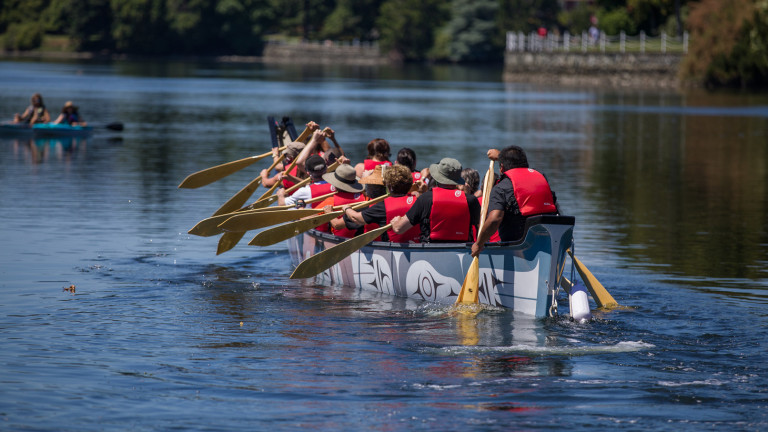 A large group paddles down the Gorge waterway in a ceremonial canoe