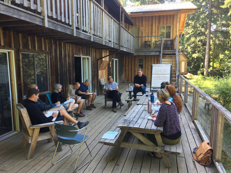 Group of adventure education students and instructor discussing topics outside lodge building