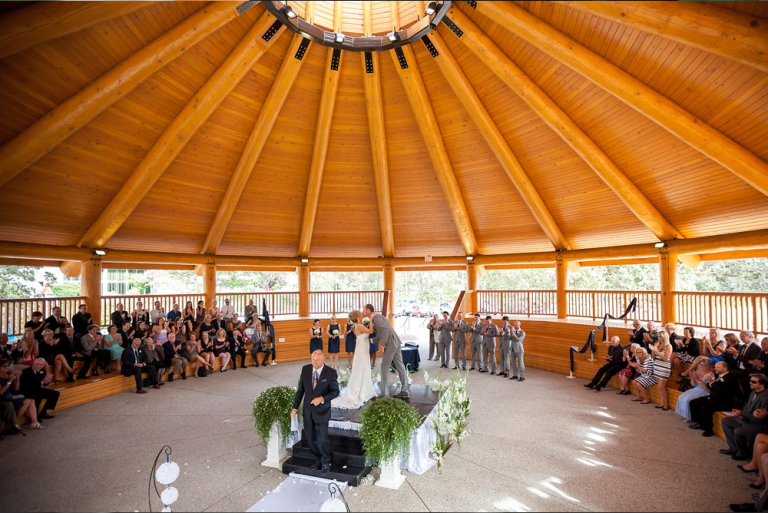 A bride and groom enjoy their first kiss with family and friends looking on.