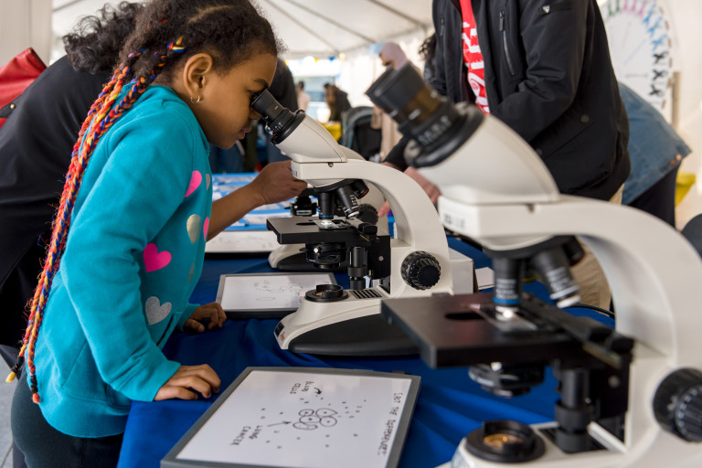 A child looks into a microscope at Science Rendezvous.